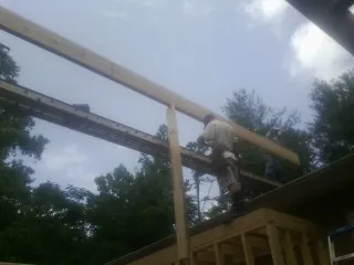 Carpenter setting a ridge beam over a new addition frame — Ice Dam Removal by Roofing Brothers in Tie Siding