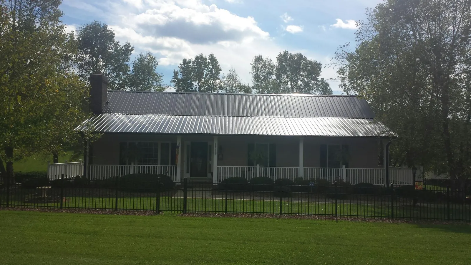 Gray metal roof on a brick ranch with a full width front porch — Gutter Guard Installation work by our crew in Tie Siding